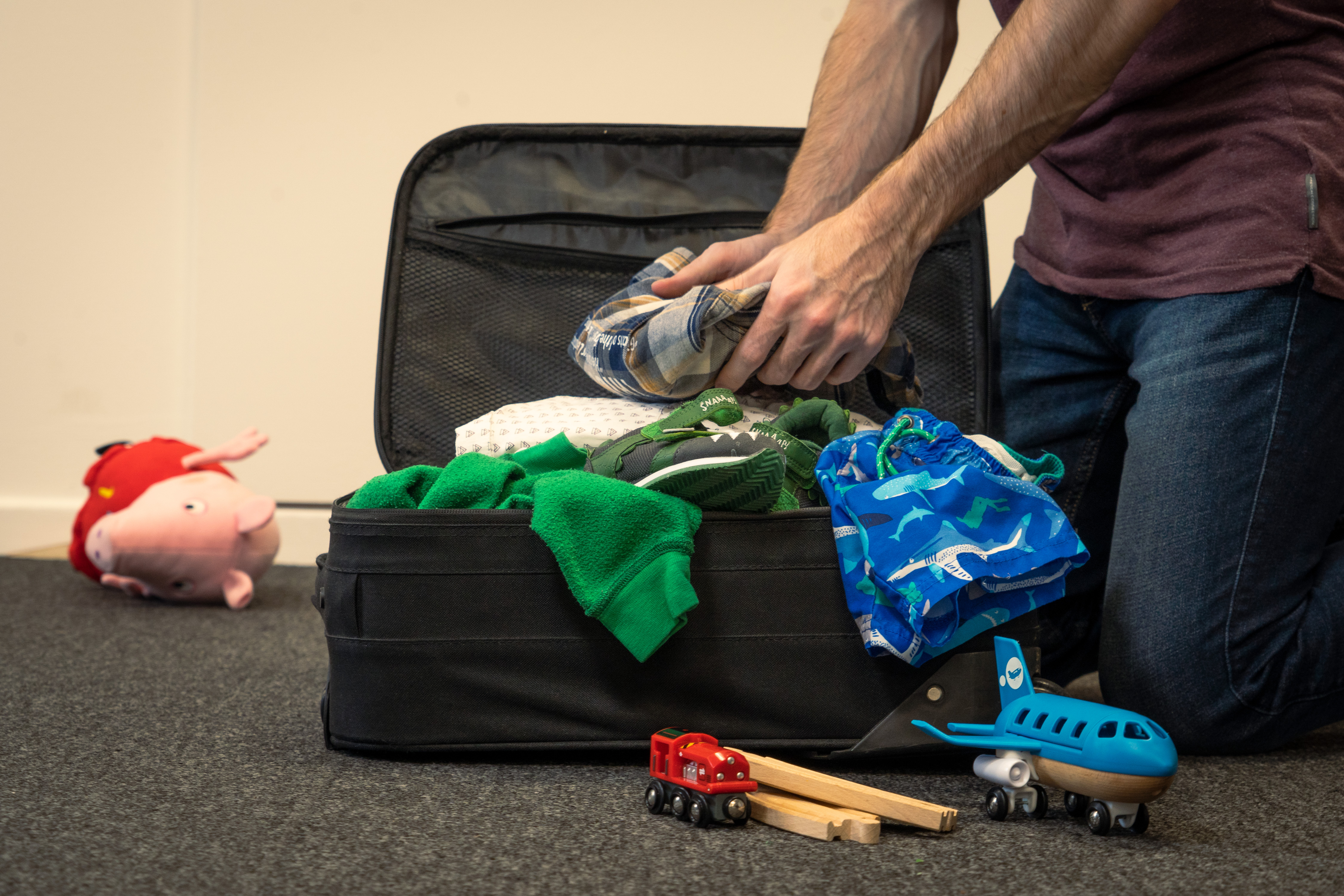 Open suitcase with folded clothing and travel items being packed for a trip.
