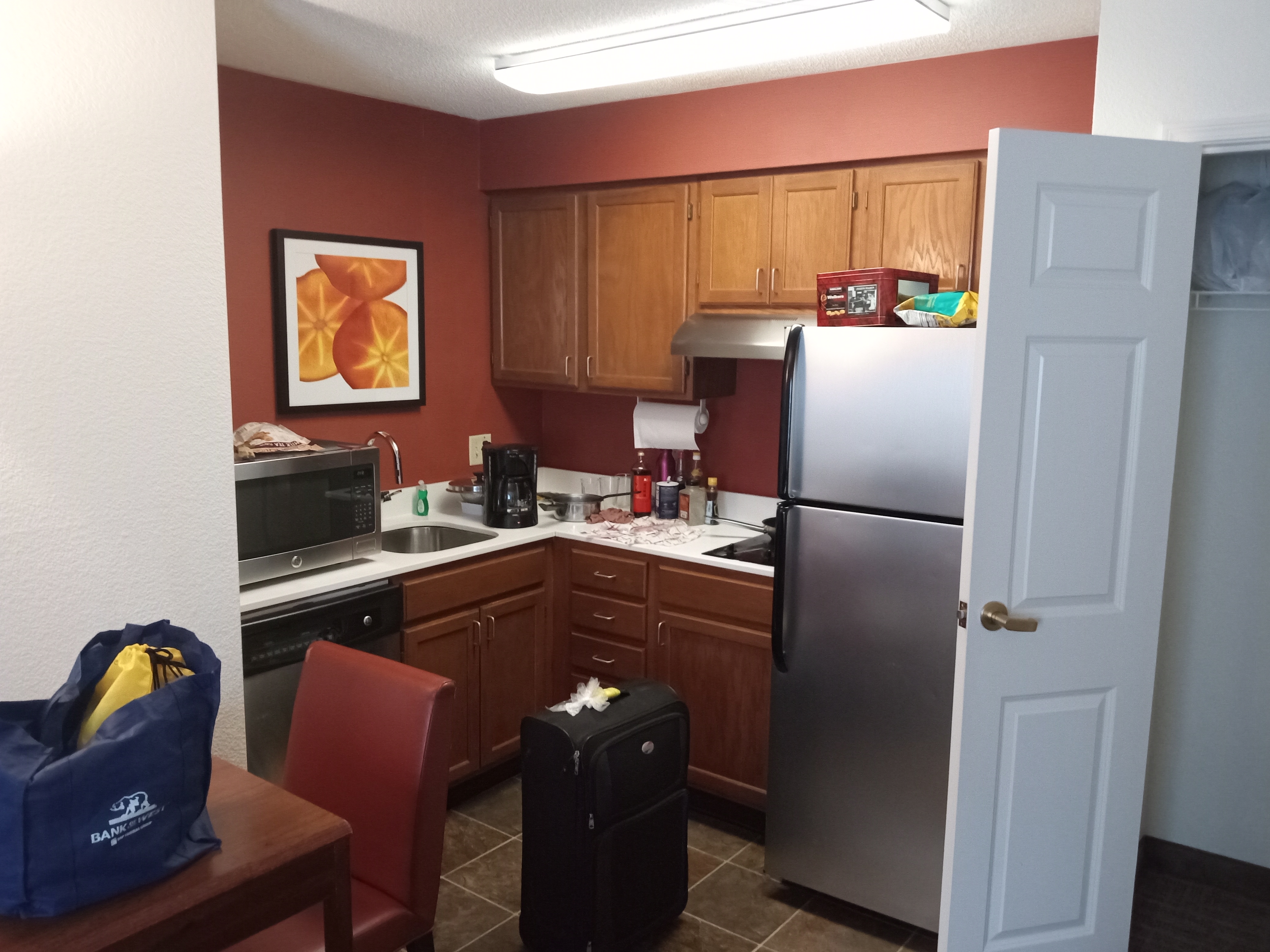 A compact hotel kitchenette with cabinets, a sink, a microwave, and a refrigerator.